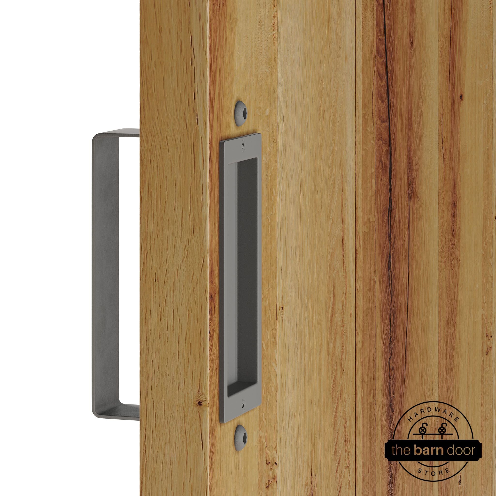 Flint gray barn door pull handle set installed on a natural wood sliding door, featuring a rectangular U-shaped pull handle on the front face and a flush recessed pull plate on the reverse side, shown in a flint gray finish.