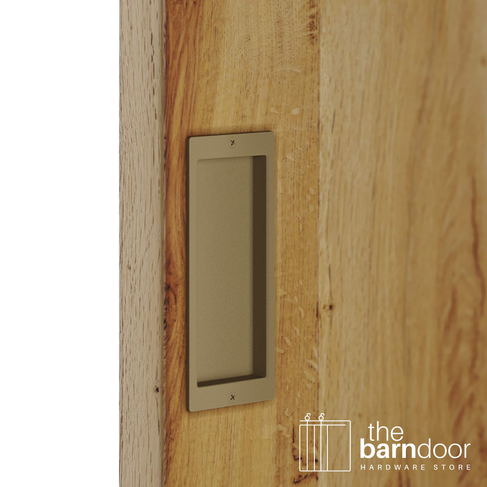 A close-up shot of a recessed rectangular flush pull handle in a gold finish, installed on a light brown wooden barn door.
