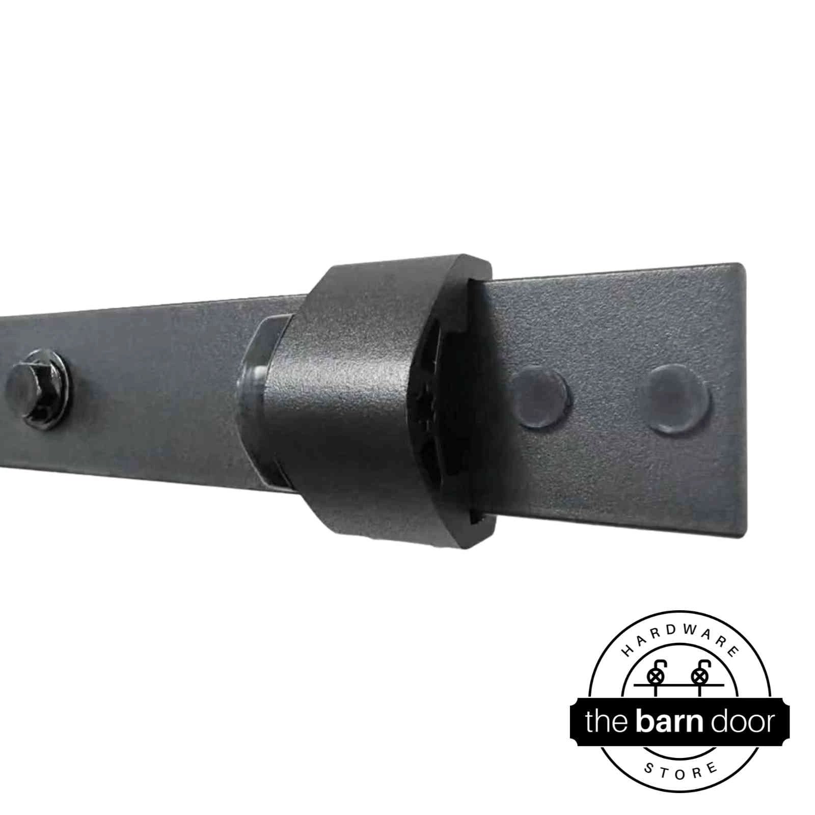 Close-up of an adjustable barn door track stop in matte black mounted to a track, showing installation detail. By The Barn Door Hardware Store.