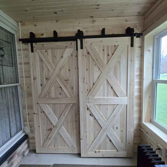 A customer install of a J-Strap double bypass barn door hardware kit in a matte black finish, shown on two sliding barn doors.