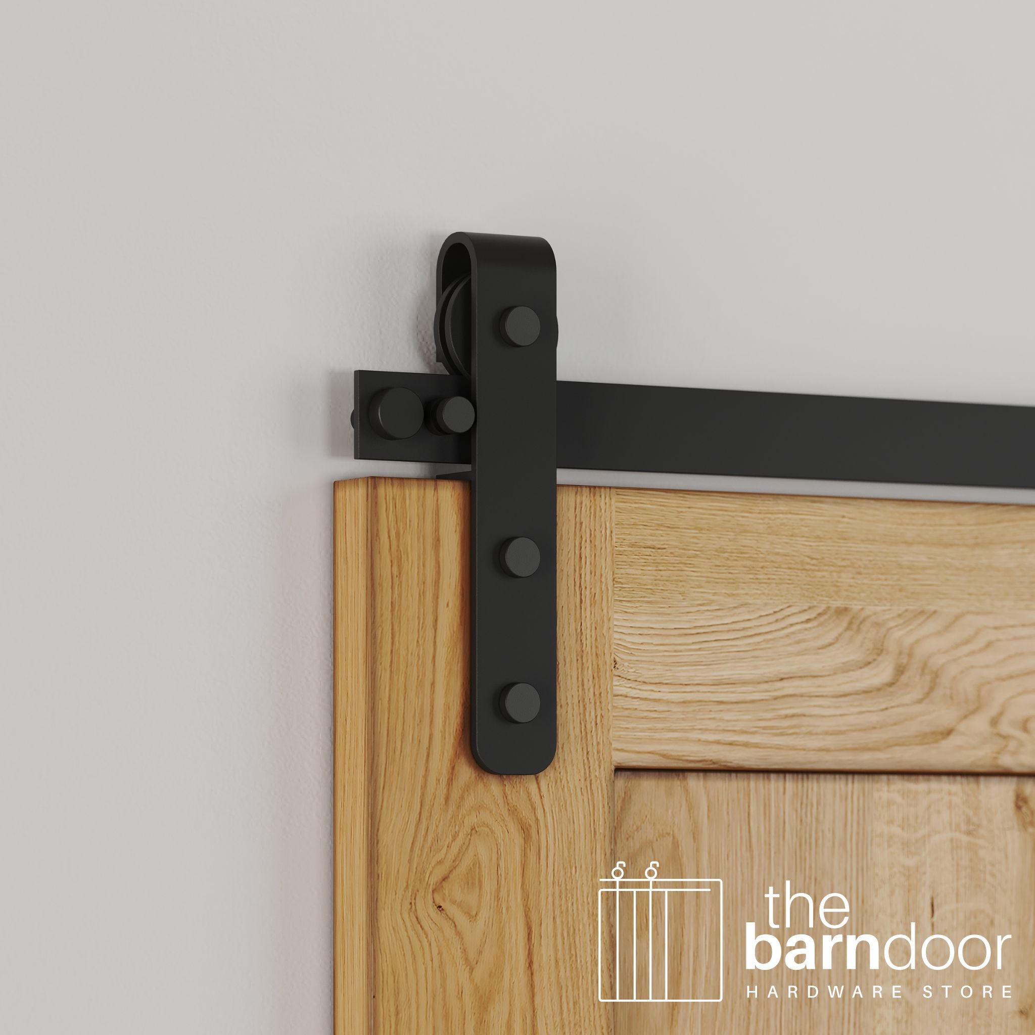 Close-up of classic Matte Black Stainless Steel J-Strap barn door hardware installed on a natural wood door, showing the curved roller.