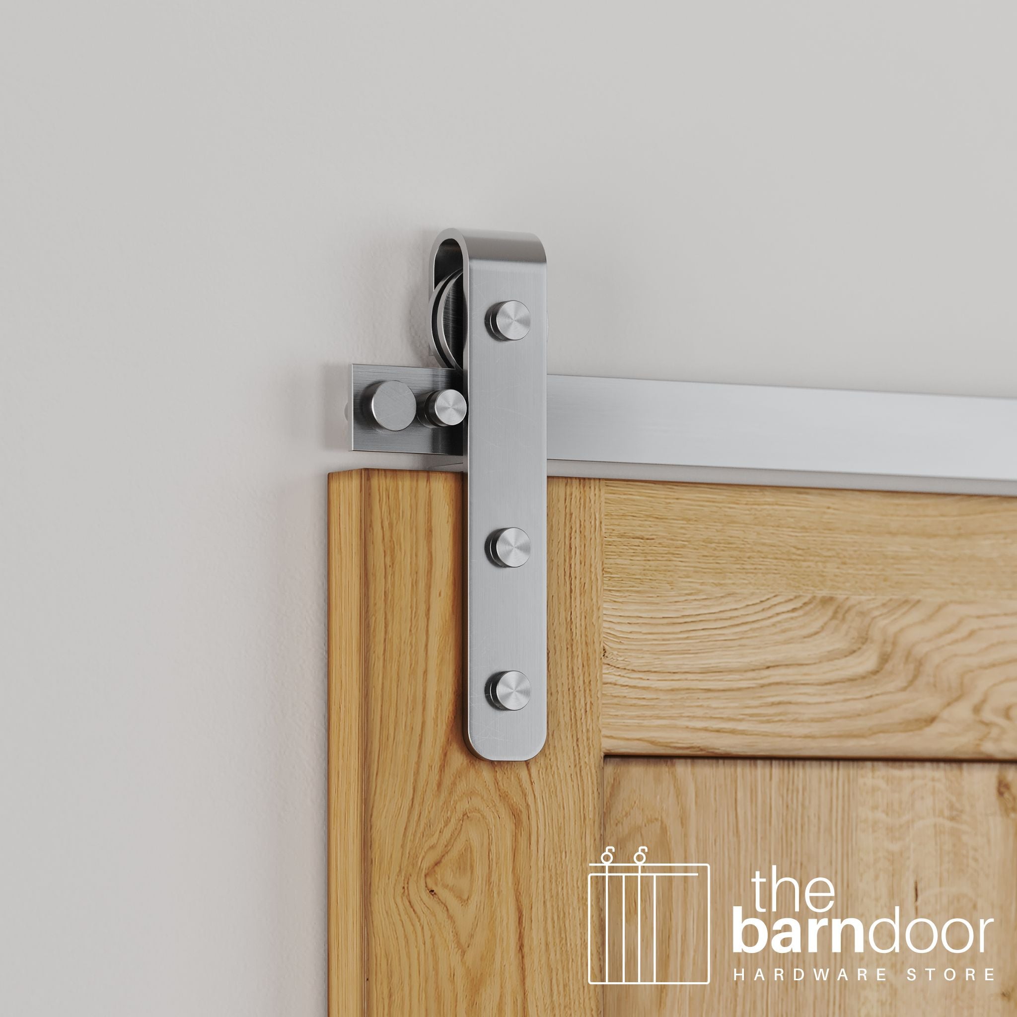 Close-up of Stainless Steel J-Strap barn door hardware installed on a natural wood door, highlighting the polished metal finish and traditional roller design.