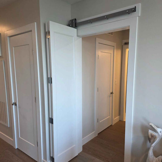 Customer installation photo of a white bifold door system running on our premium sliding barn door hardware with a modern, silver metallic finish.