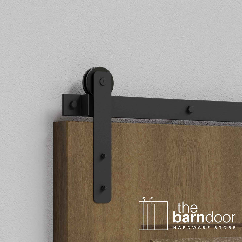 Close-up of Matte Black Straight Strap Single Track barn door hardware installed on a wooden door panel.