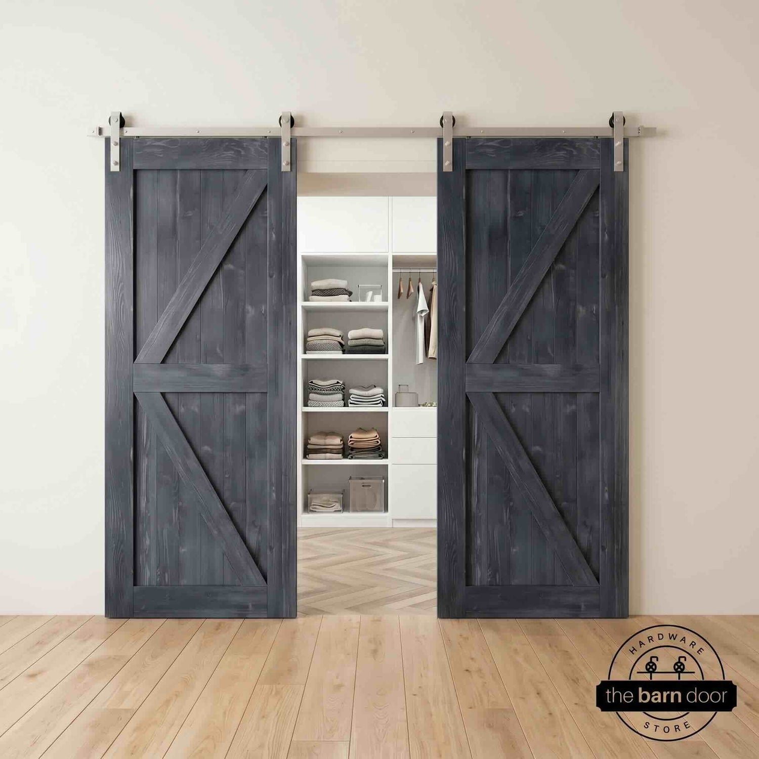 Two wood double barn doors with a two-panel vertical plank design in a navy stain, installed with brushed nickel sliding hardware, partially revealing a living room area.