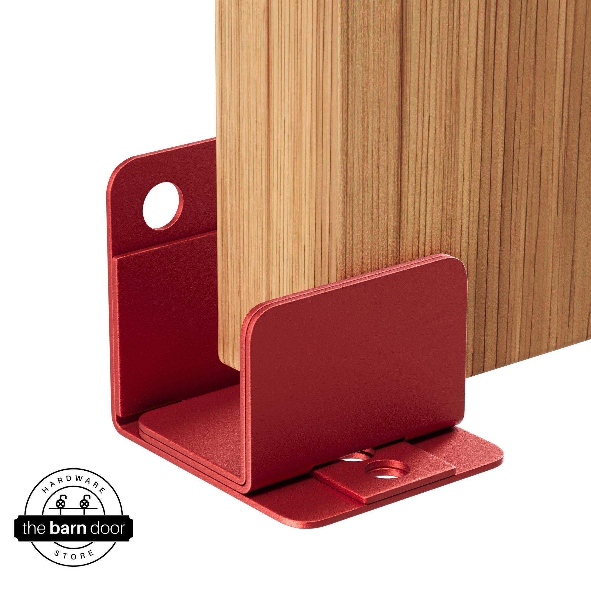 A red U-shaped floor guide with a side plate, holding a light wood barn door in place.