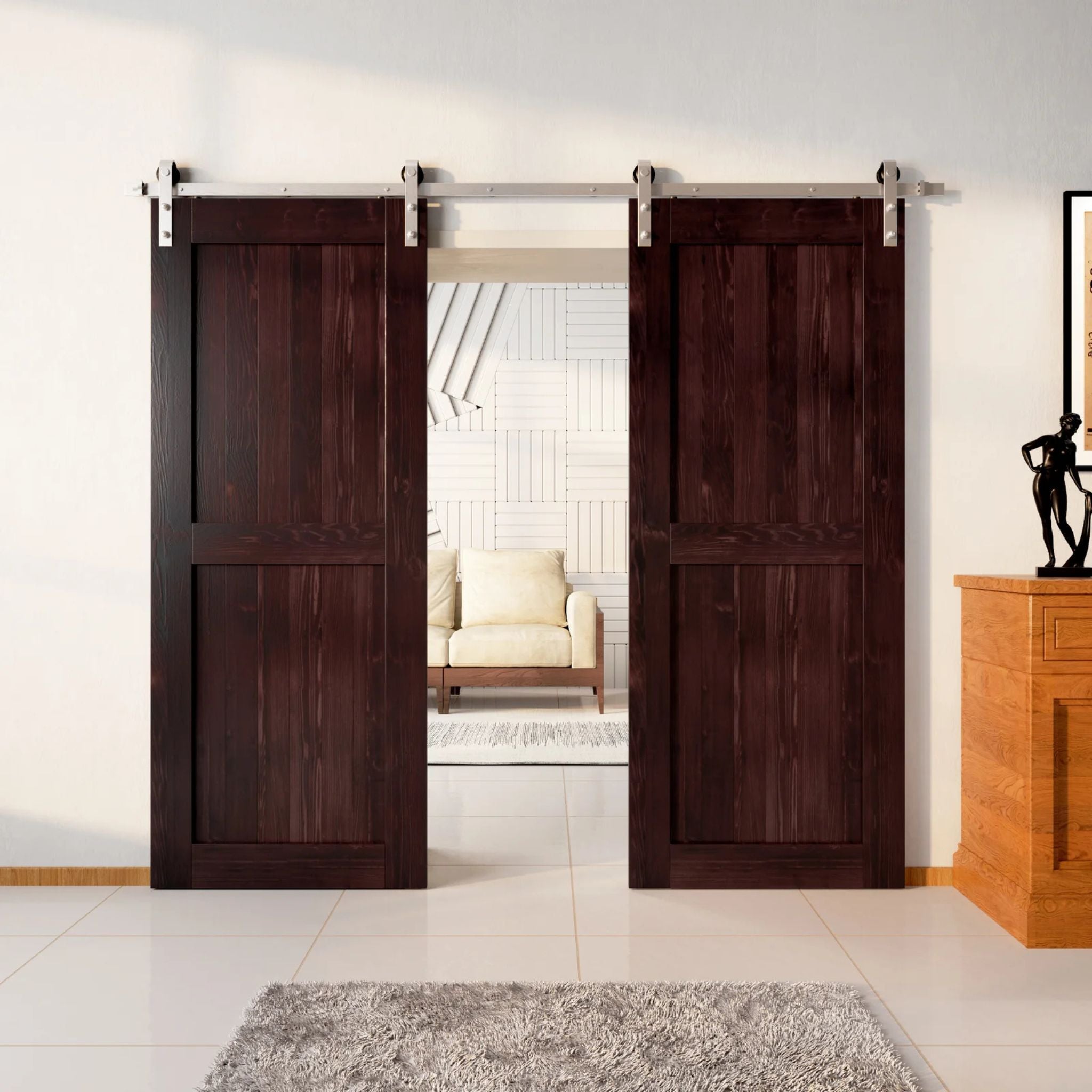 Two wood double barn doors with a two-panel vertical plank design in a rich, dark Red Mahogany stain, installed with brushed nickel sliding hardware, partially revealing a living room area.