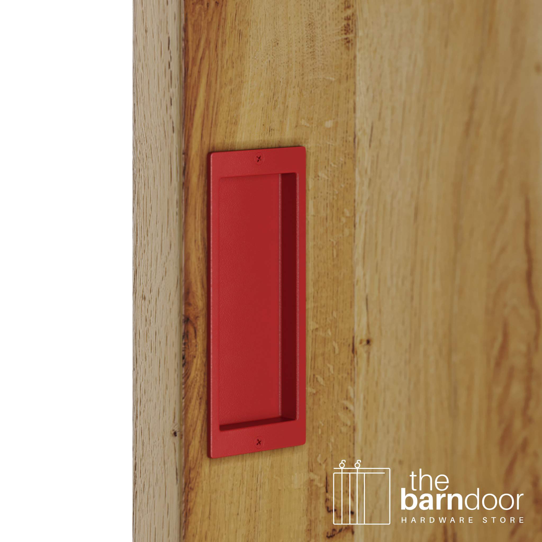 A close-up shot of a recessed rectangular flush pull handle in a red finish, installed on a light brown wooden barn door.