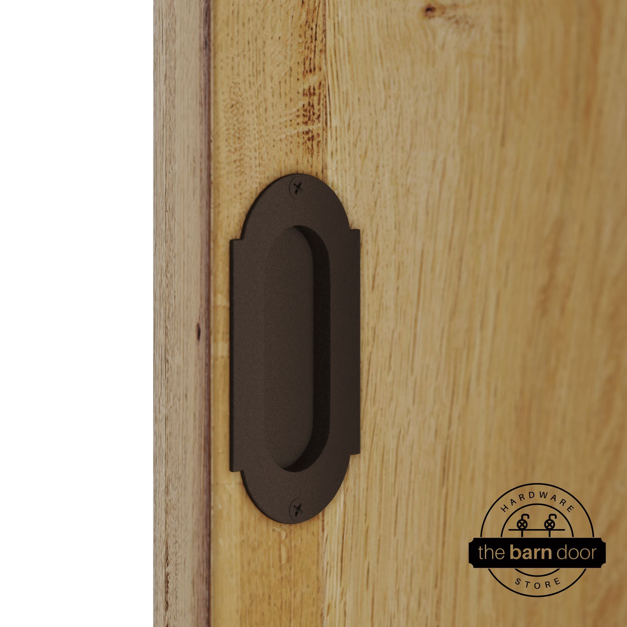 Rustic brown flush pull handle with full radius wings mounted on a light oak barn door, brushed silver finish with oval recessed grip and four mounting screws
