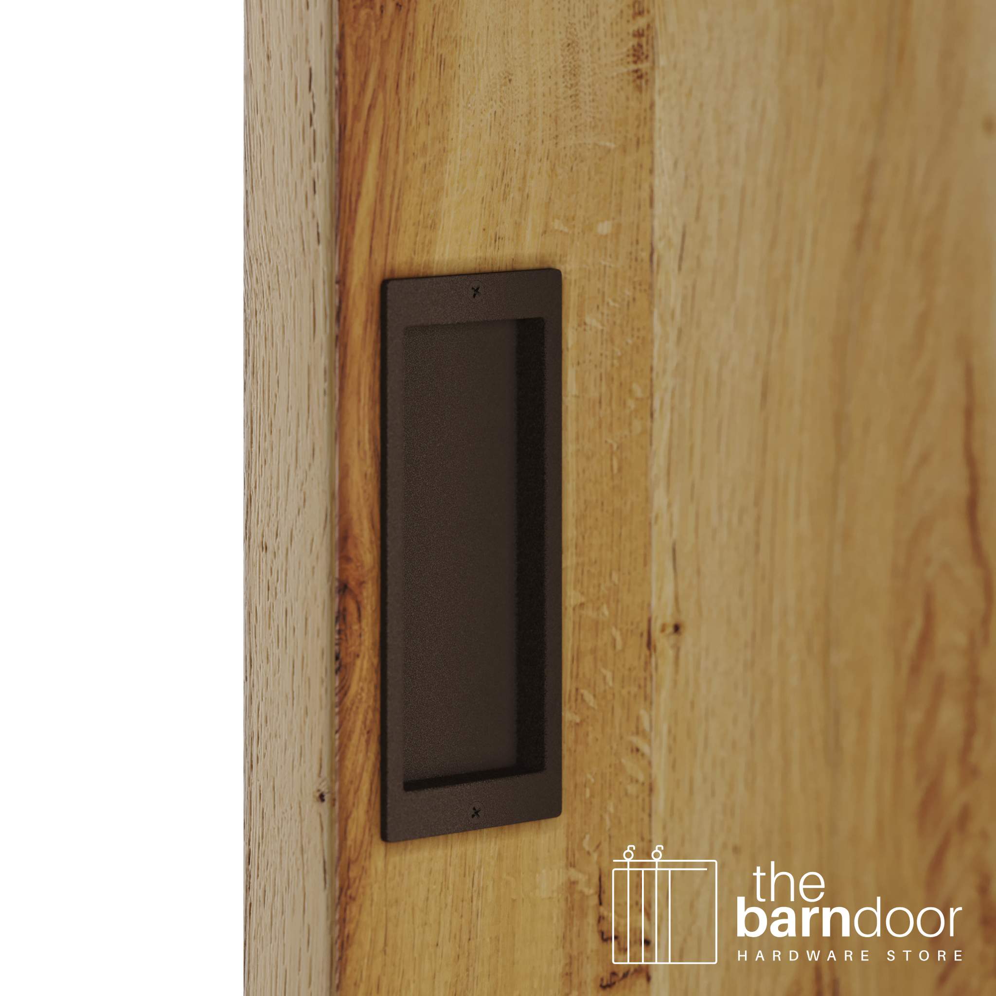 A close-up shot of a recessed rectangular flush pull handle in a rustic brown finish, installed on a light brown wooden barn door.