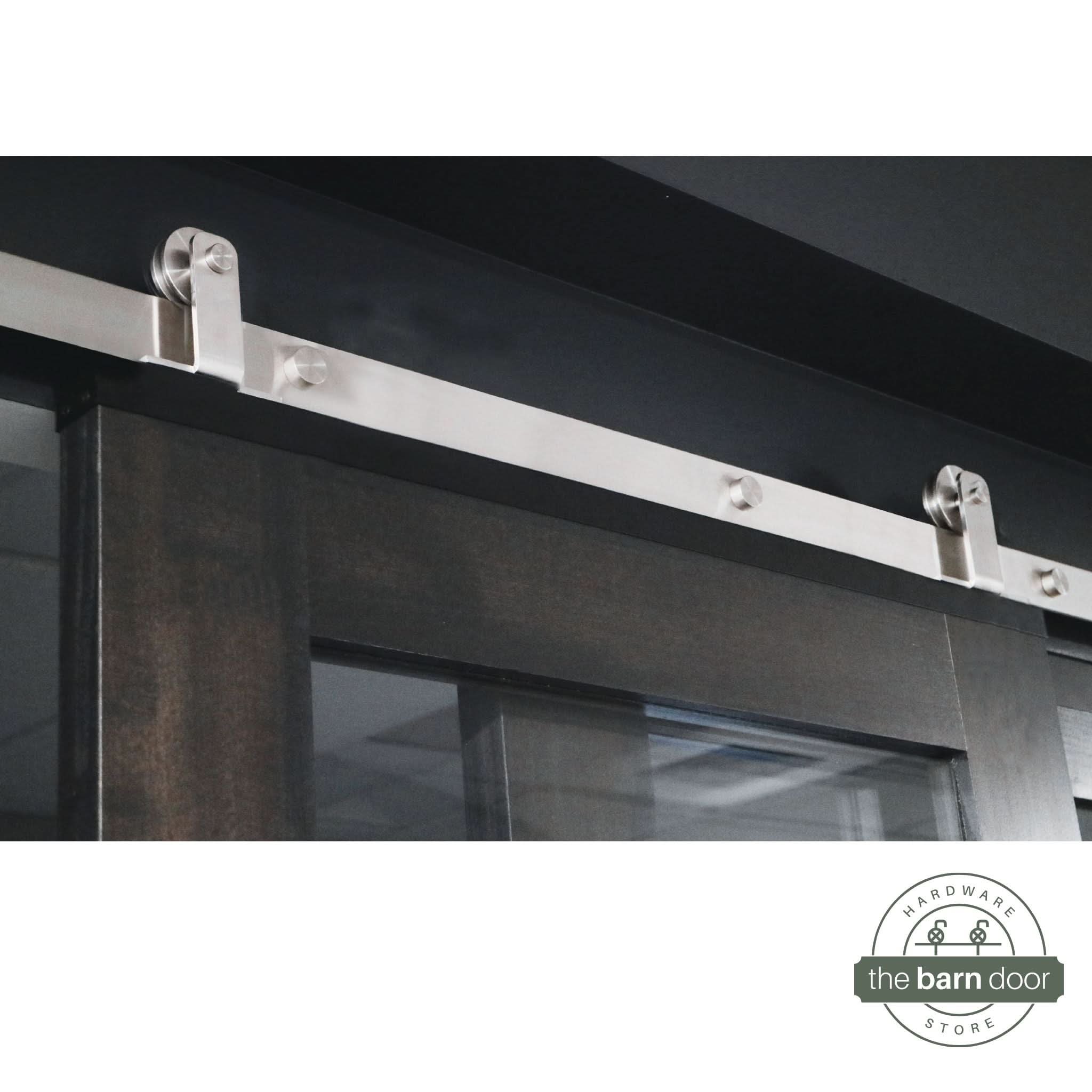 Straight Top Mount stainless steel barn door hardware kit installed on a single wood door, showcasing the minimalist, concealed roller design.