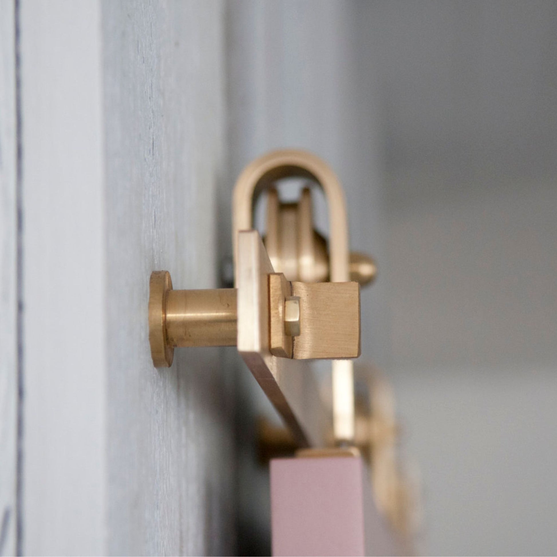 Side View of Top Mount Brass Barn Door Hardware on Pink Door