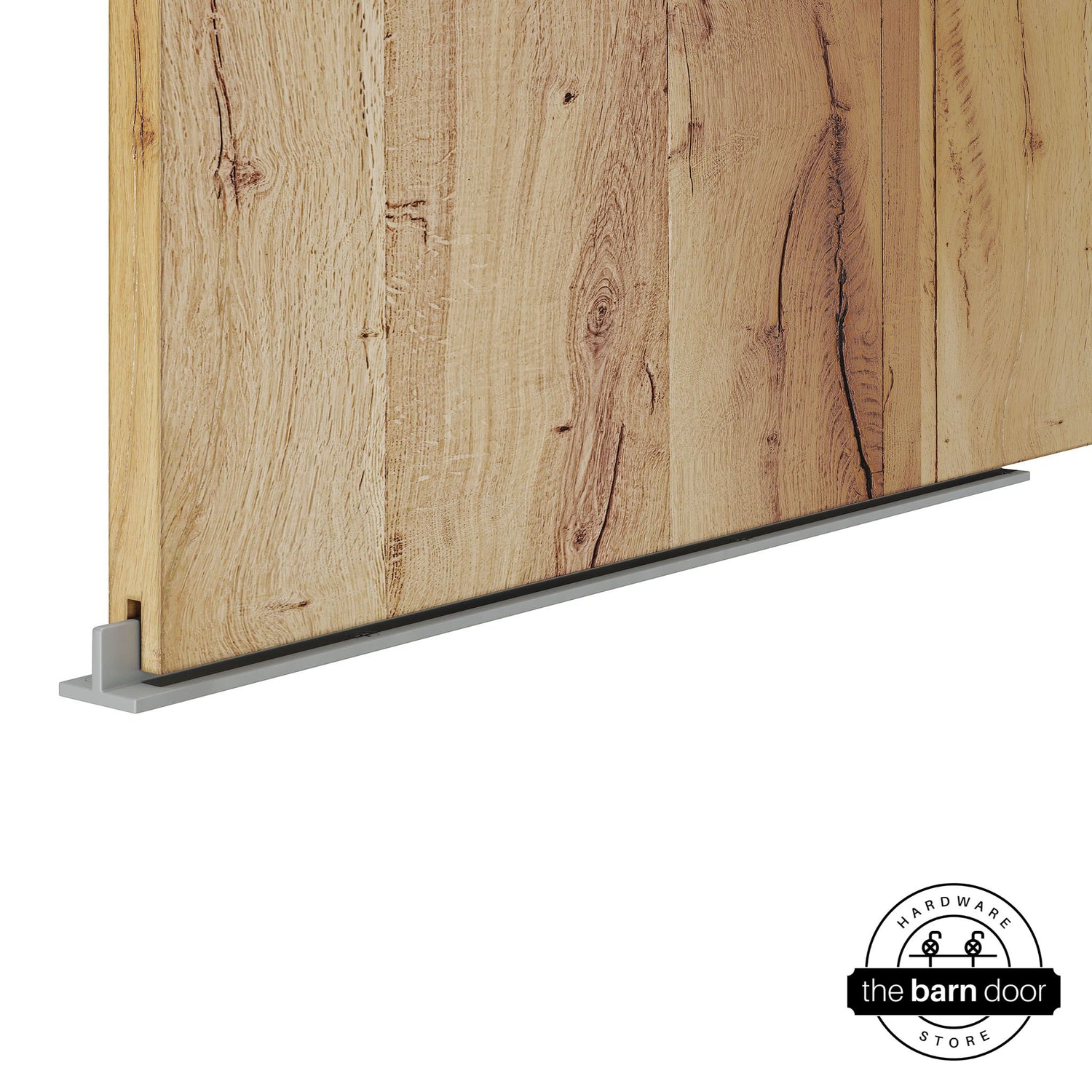 Silver Metallic continuous T-guide floor track for barn doors by The Barn Door Hardware Store. Close-up of a heavy-duty bottom floor guide installed on a rustic wood door for stabilization and smooth sliding operation.