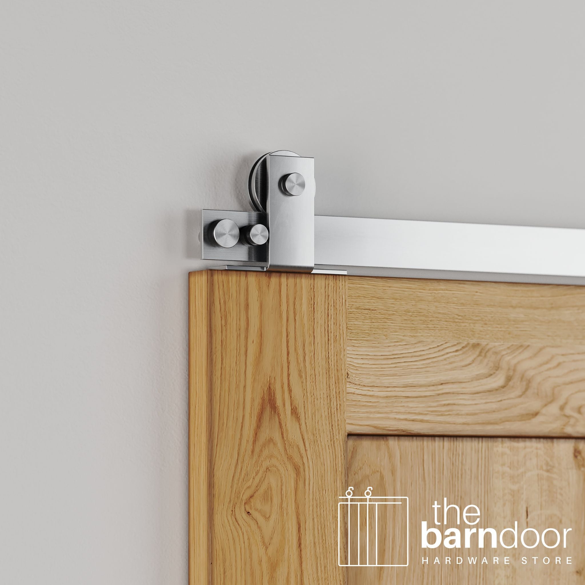 Close-up of Stainless Steel Soft-Corner Top Mount barn door hardware installed on the top edge of a natural oak wood door, highlighting the sleek, minimalist design.