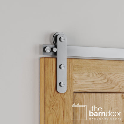Close-up of Stainless Steel Straight Strap barn door hardware installed on a natural oak wood door, highlighting the modern, industrial strap design.