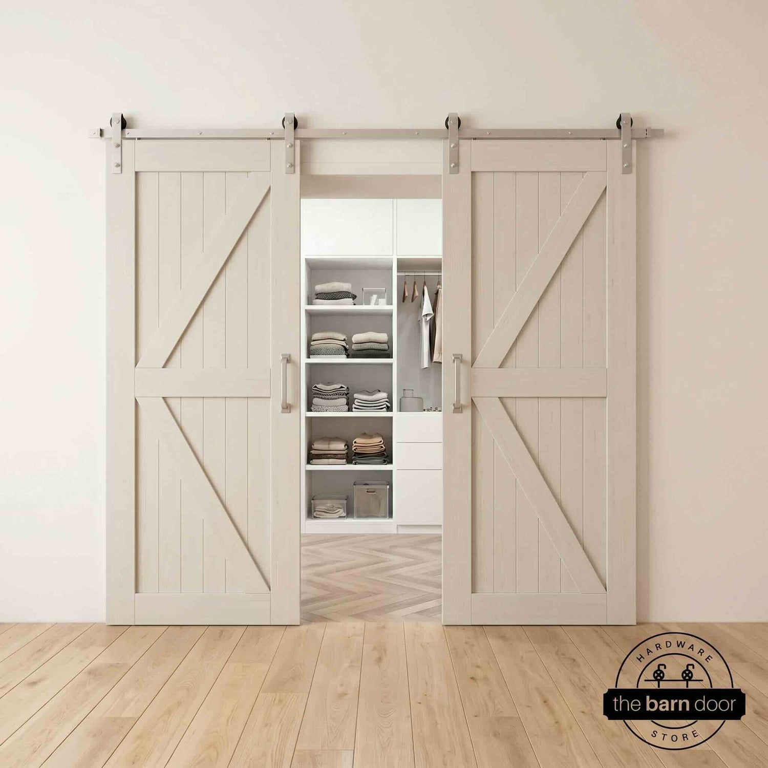 Two wood double barn doors with a two-panel vertical plank design in a tinsmith gray stain, installed with brushed nickel sliding hardware, partially revealing a living room area.