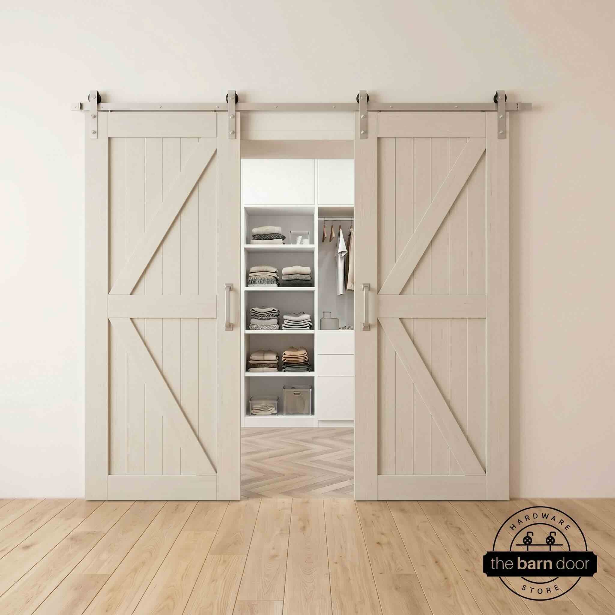 Two wood double barn doors with a two-panel vertical plank design in a tinsmith gray stain, installed with brushed nickel sliding hardware, partially revealing a living room area.