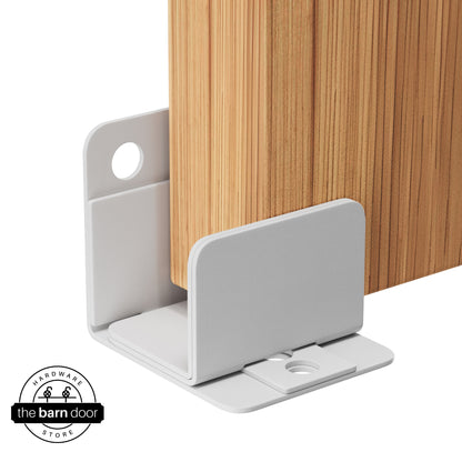 A rocket white U-shaped floor guide with a side plate, holding a light wood barn door in place.