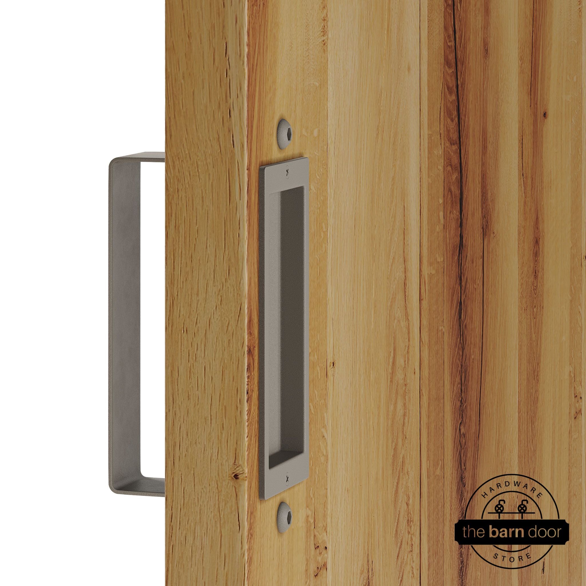 White bronze barn door pull handle set installed on a natural wood sliding door, featuring a rectangular U-shaped pull handle on the front face and a flush recessed pull plate on the reverse side, shown in a white bronze finish.