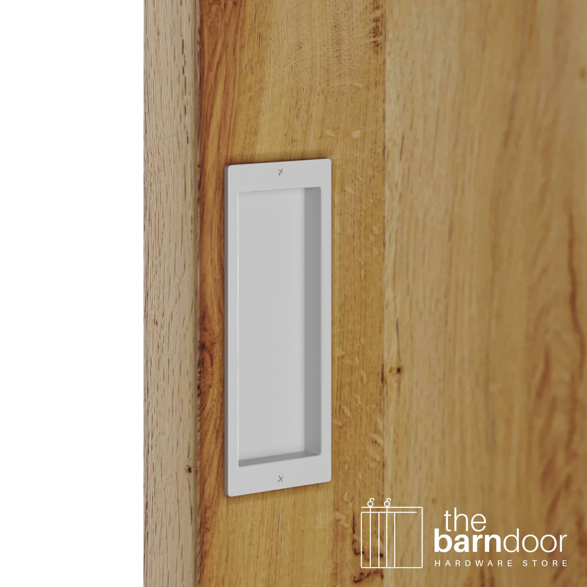 A close-up shot of a recessed rectangular flush pull handle in a rocket white finish, installed on a light brown wooden barn door.