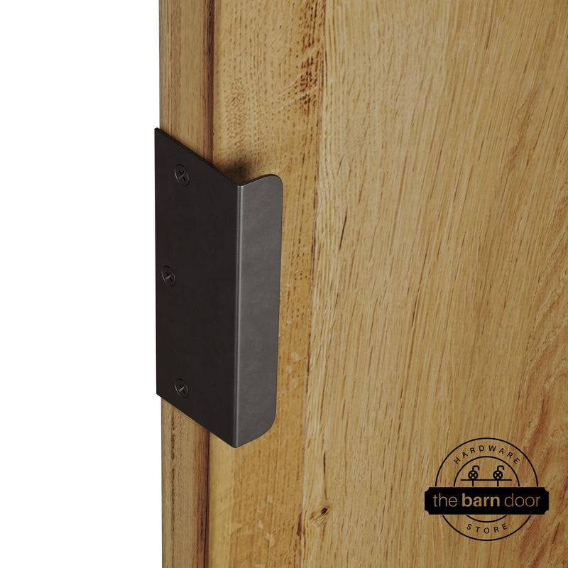 Arch bronze sliding barn door edge pull handle on natural wood door edge