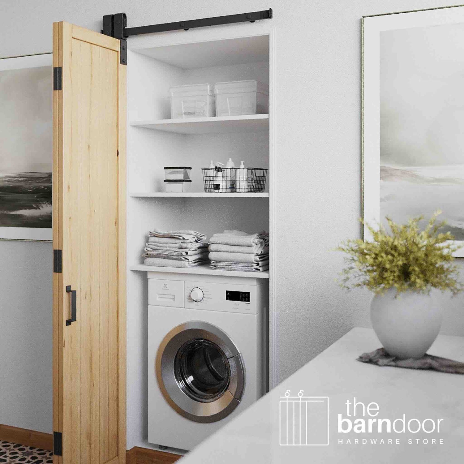 Wooden bifold barn door opening to reveal a laundry room with a washing machine, shelves, and decor.