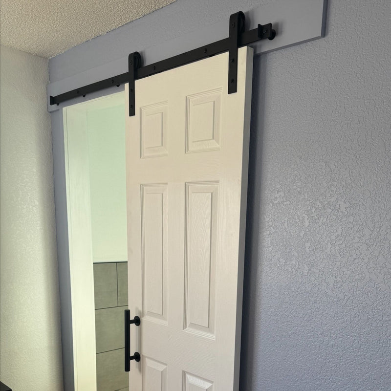 White sliding door with black hardware in a room with light gray walls.