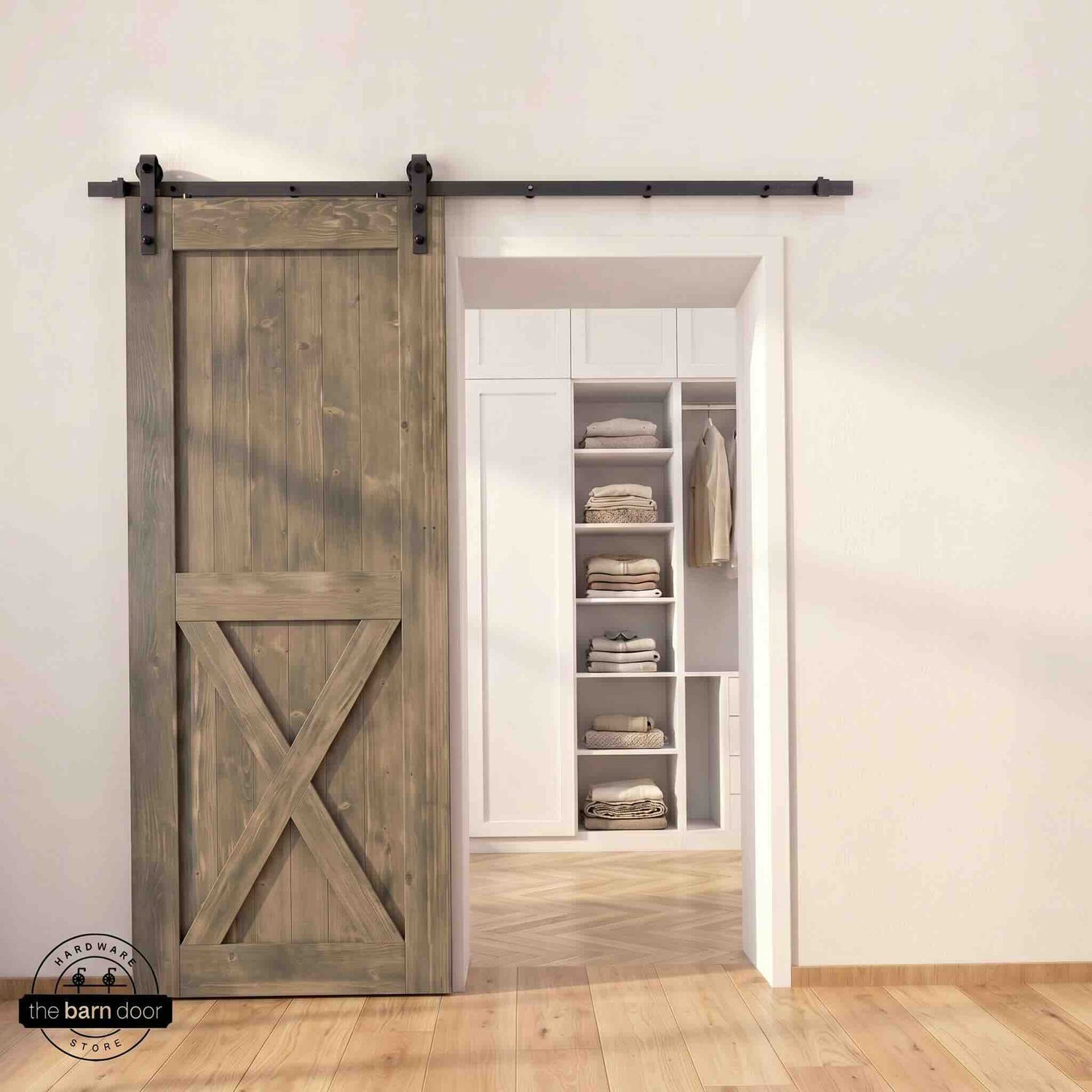 Half-X barn door in classic gray stain finish with matte black sliding barn door hardware, open to a white built-in closet with herringbone hardwood floors