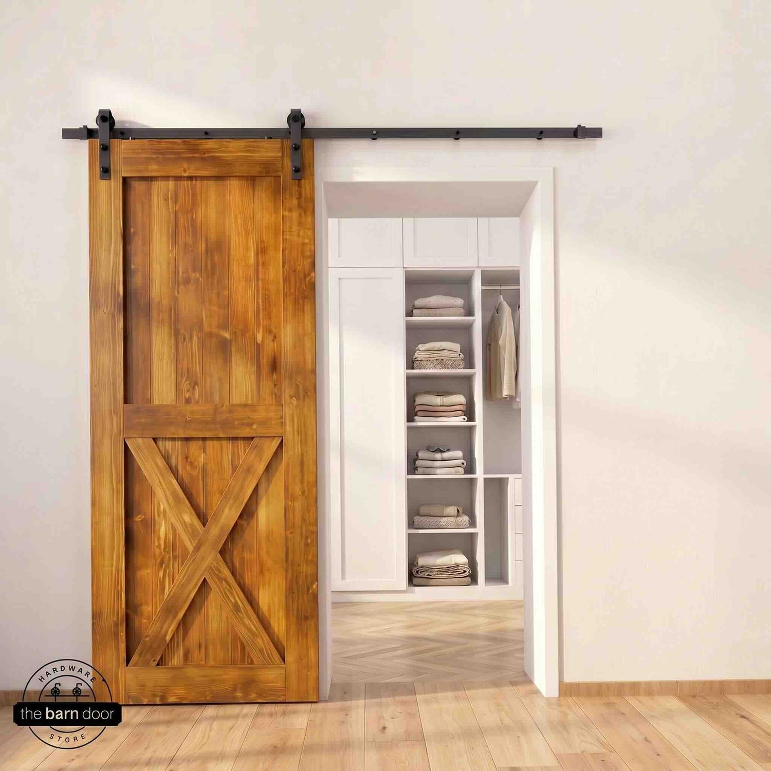 Half-X barn door in Early American stain finish with matte black sliding barn door hardware, open to a white built-in closet with herringbone hardwood floors