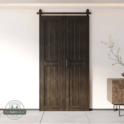 Two-panel bifold barn door in an ebony finish, installed and fully closed in a modern interior, showing the top-mount Matte Black track.