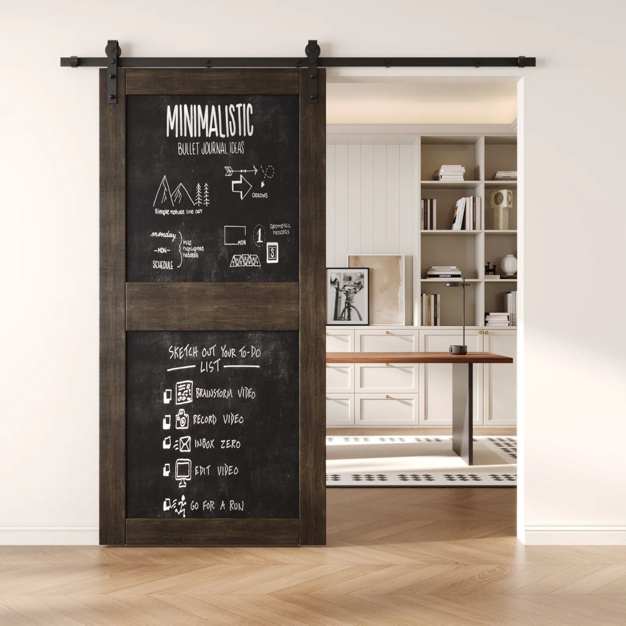 A ebony two-panel chalkboard barn door mounted on a sleek black sliding track, shown partially open to reveal a modern home office with built-in white shelving.