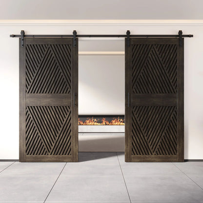 Two fully closed double barn doors in a ebony finish, featuring a bold, intricate diamond slat pattern. The doors are installed with black sliding hardware against a white wall, revealing a modern linear fireplace in the space behind them.