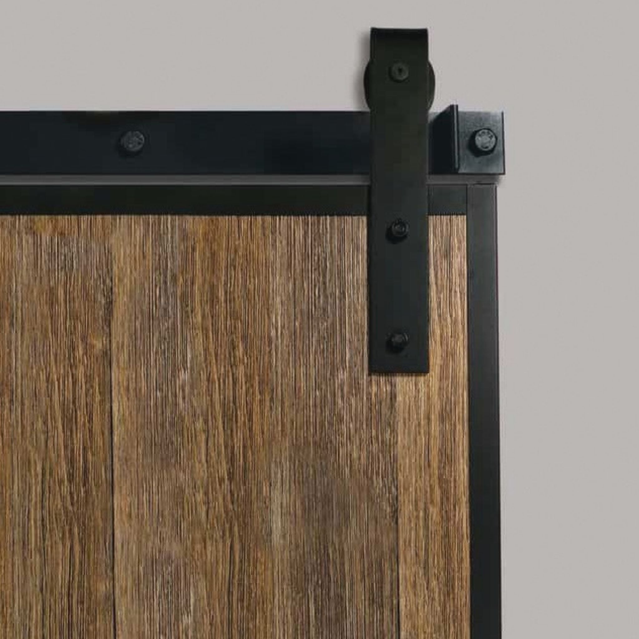 Close-up of Goldberg Brothers Barn Door Edge Wrap corner detail on a rustic wood sliding door with black powder-coated steel channels and J-strap roller hanger