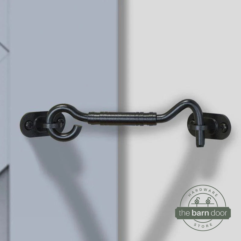 Matte black hook and eye barn door latch securing a light blue door to the adjacent wall