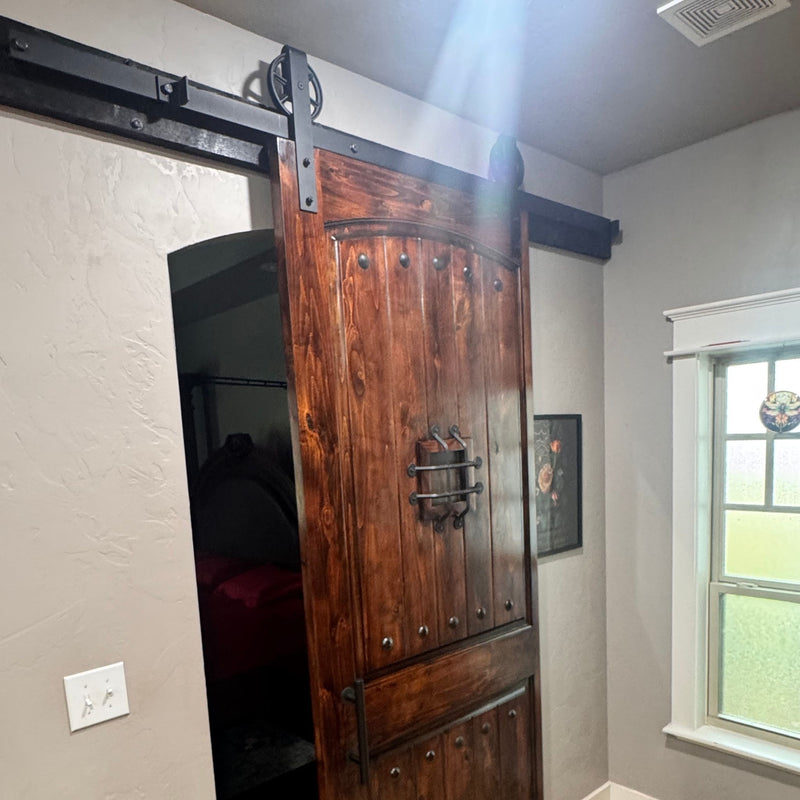 Industrial wooden sliding barn door in a room with a window and light switch.