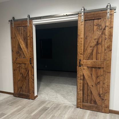 Wooden sliding barn doors in a room with a dark hallway.
