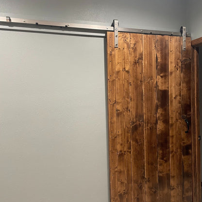 Wooden sliding barn door with j-strap brushed nickel barn door hardware on a gray wall