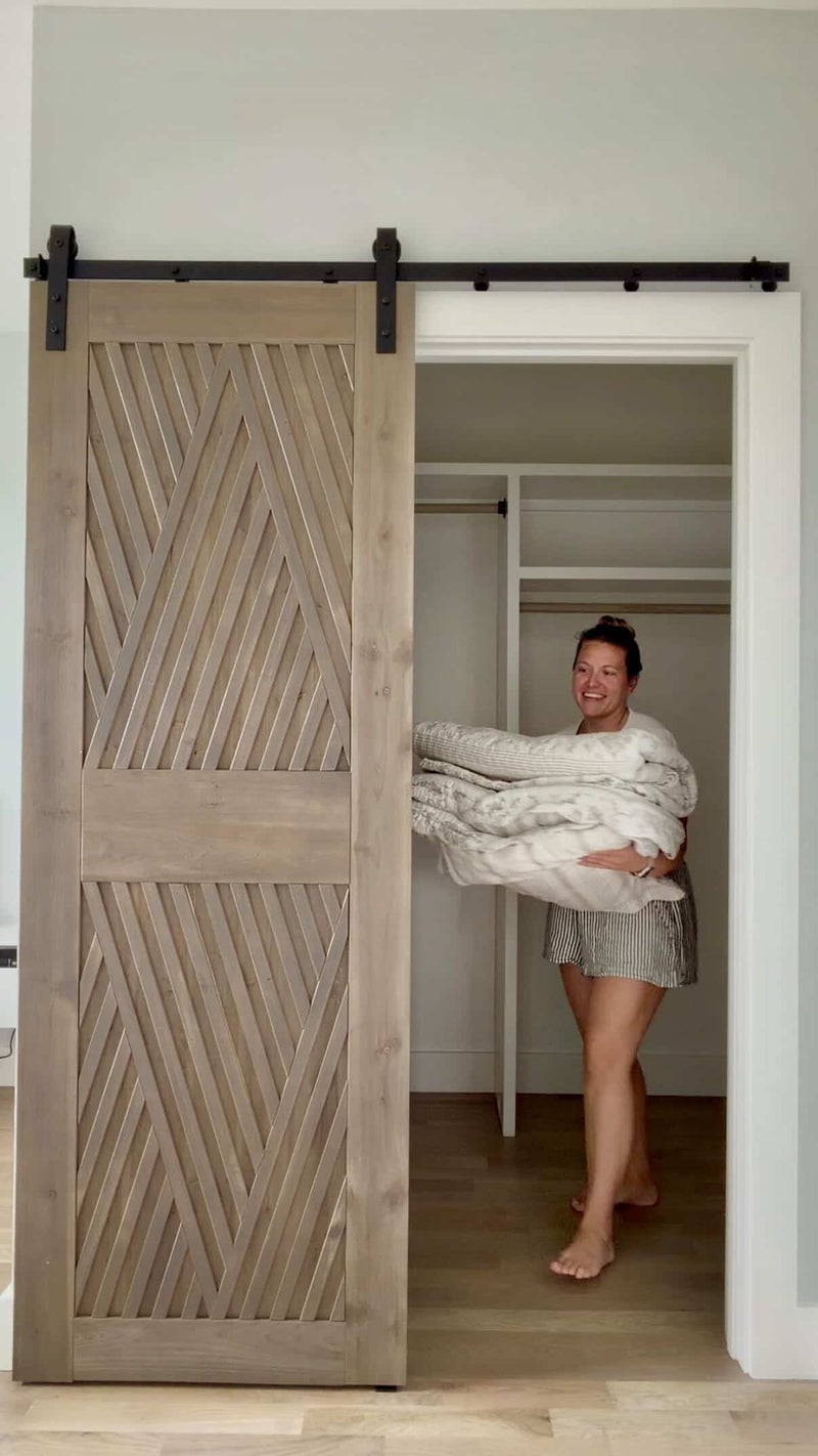 Woman carrying folded clothes in a room with a wooden sliding door