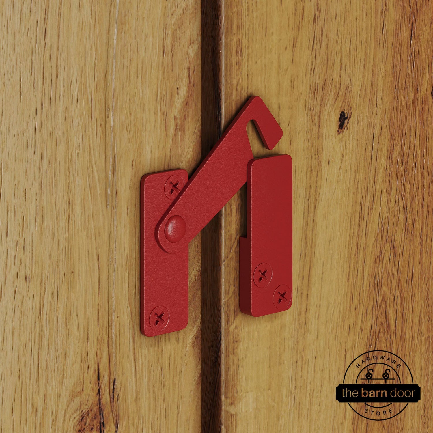 Red privacy latch for biparting barn doors, shown latched across two wood door panels