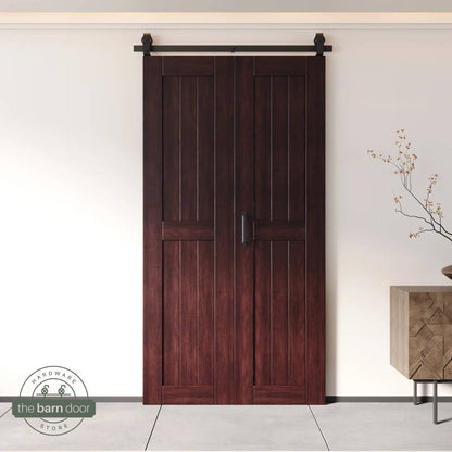 Two-panel bifold barn door in a red mahogany finish, installed and fully closed in a modern interior, showing the top-mount Matte Black track.