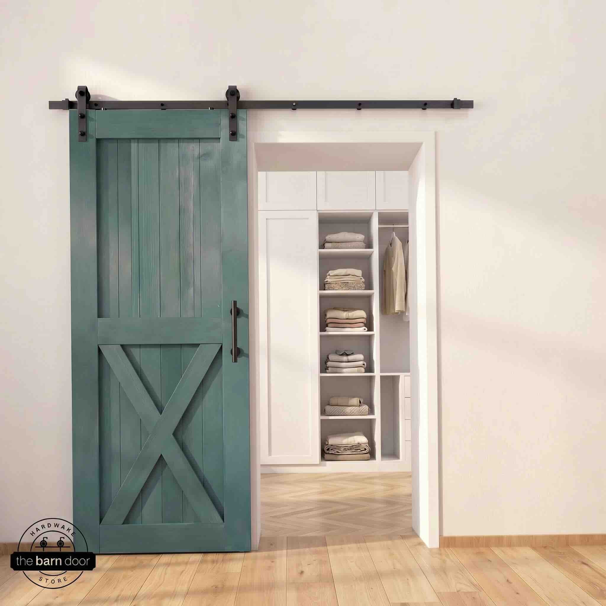 Half-X barn door in royal pine stain finish with matte black sliding barn door hardware, open to a white built-in closet with herringbone hardwood floors