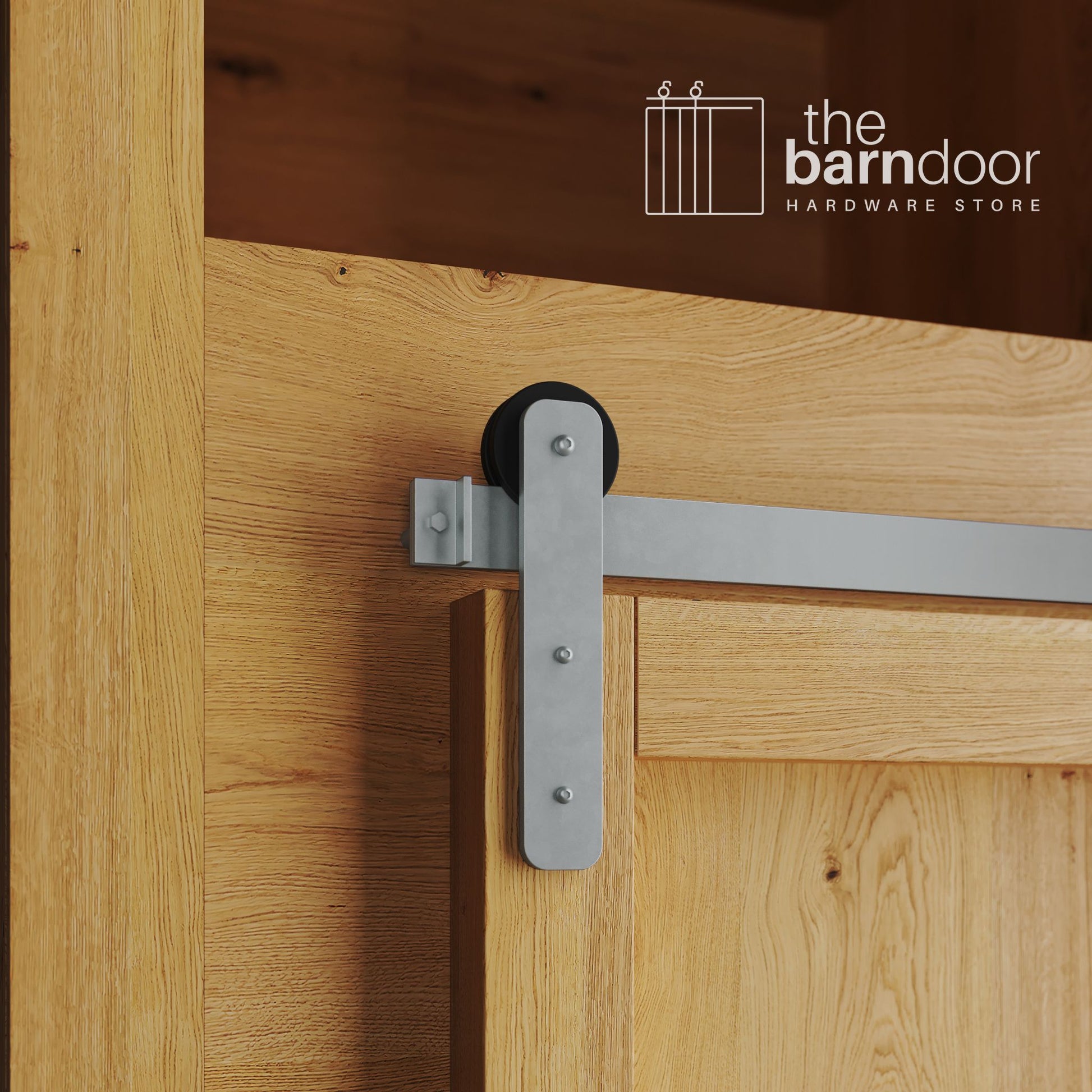 A close-up photograph of a natural oak cabinet with a sliding mini barn door, featuring a silver metallic straight-strap hanger and a silver metallic track system.