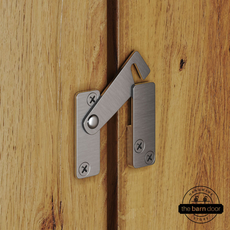 Stainless steel privacy latch for biparting barn doors, shown latched across two wood door panels