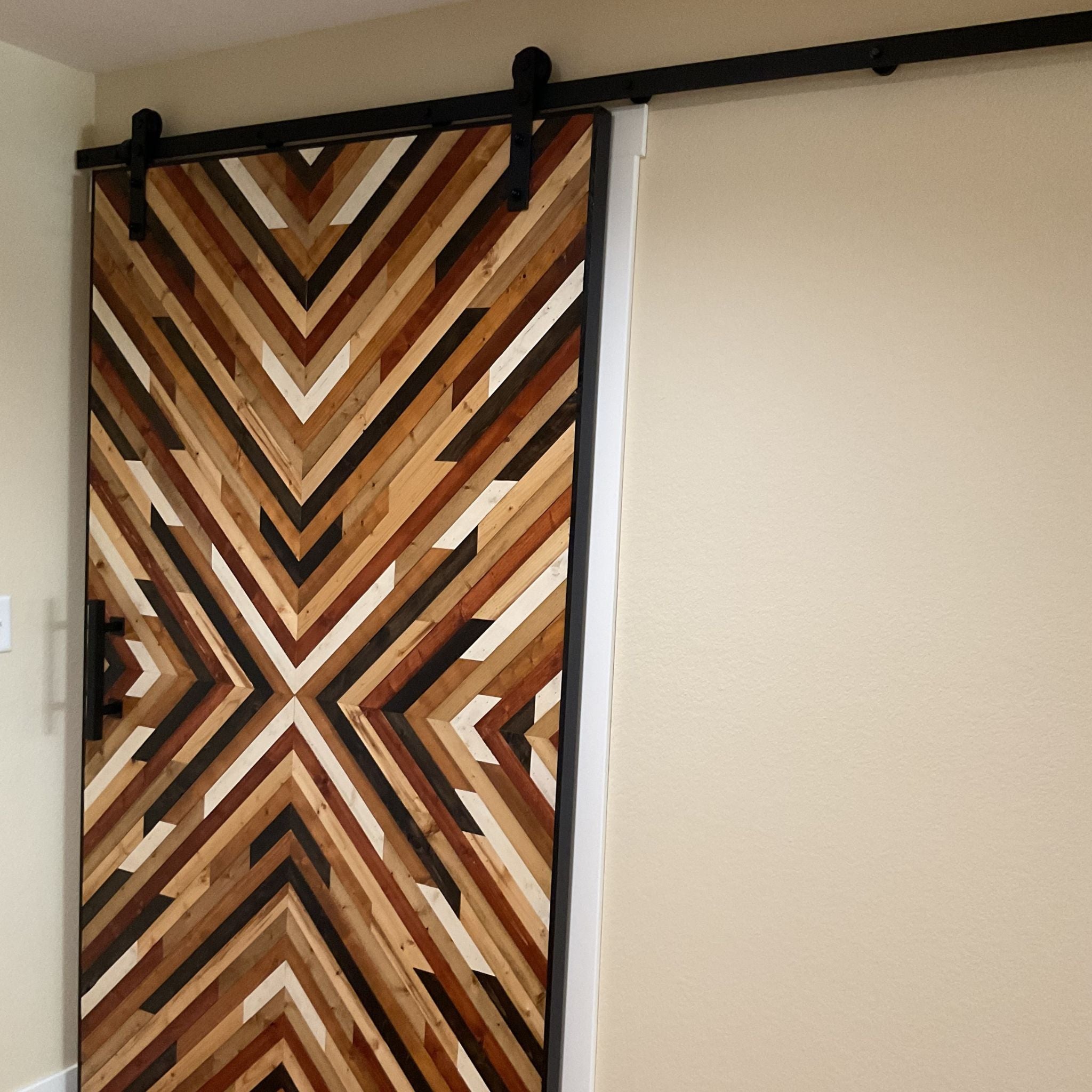 Barn door with a wooden pattern sliding open in a room.