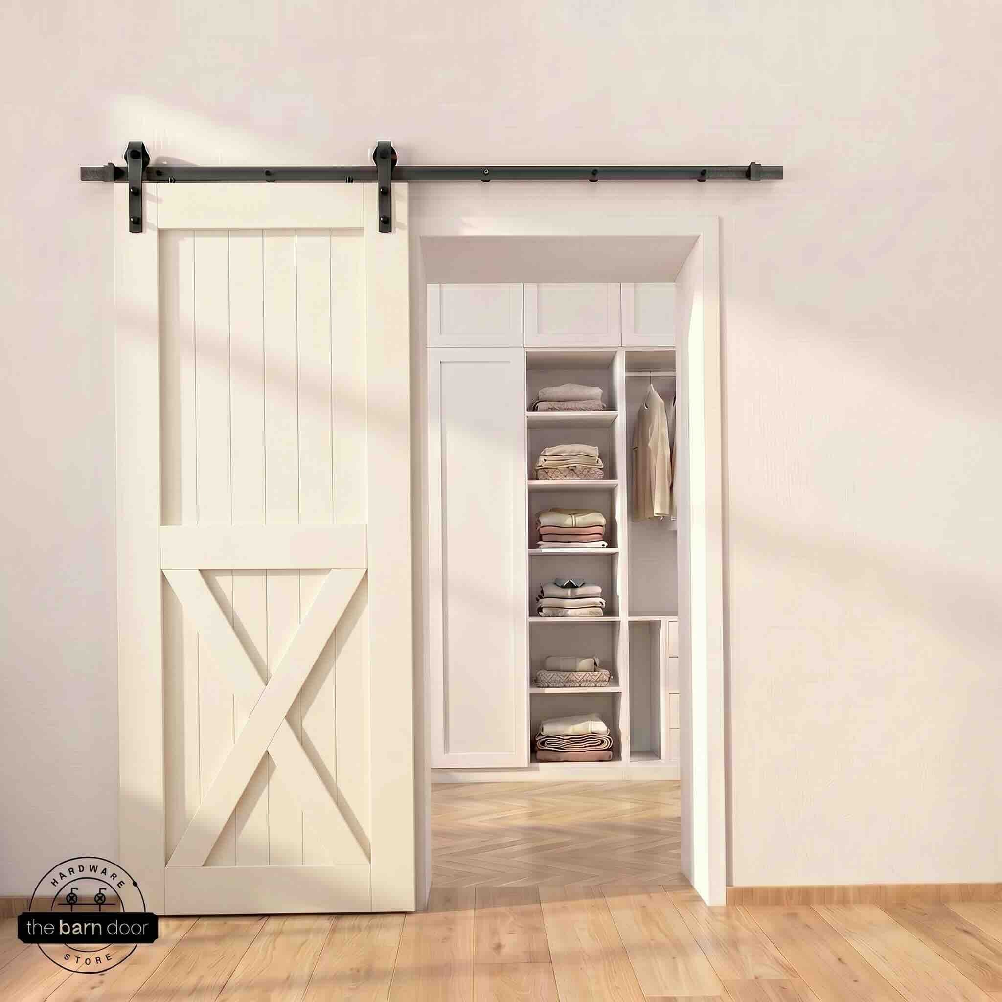 Half-X barn door in tinsmith gray stain finish with matte black sliding barn door hardware, open to a white built-in closet with herringbone hardwood floors