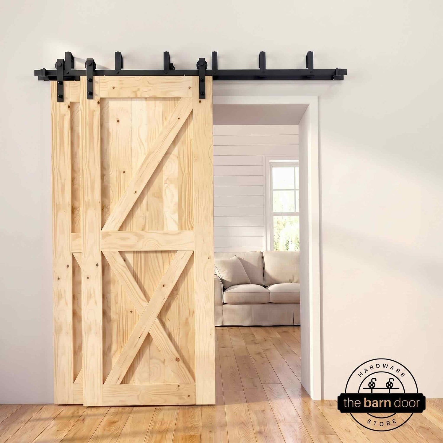 Unfinished pine bypass barn door with  black hardware track, mounted over living room entryway