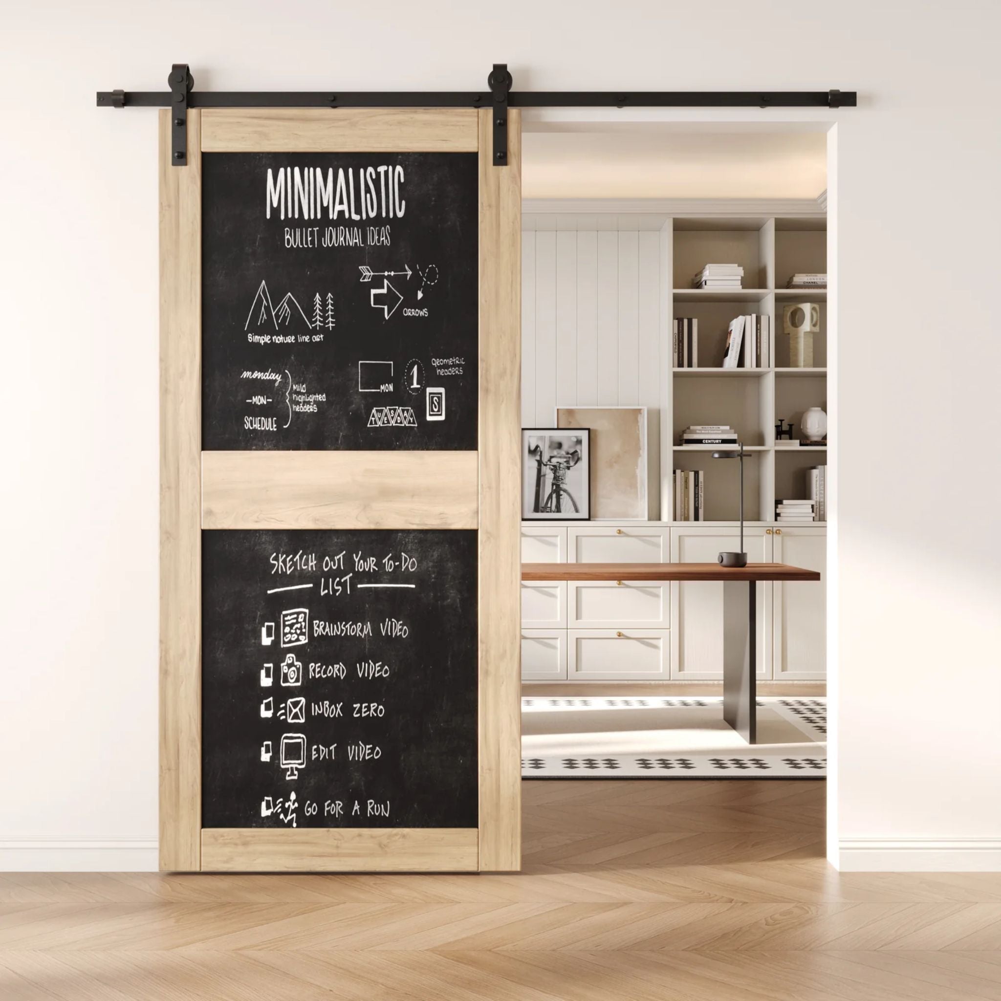An unfinished two-panel chalkboard barn door mounted on a sleek black sliding track, shown partially open to reveal a modern home office with built-in white shelving.